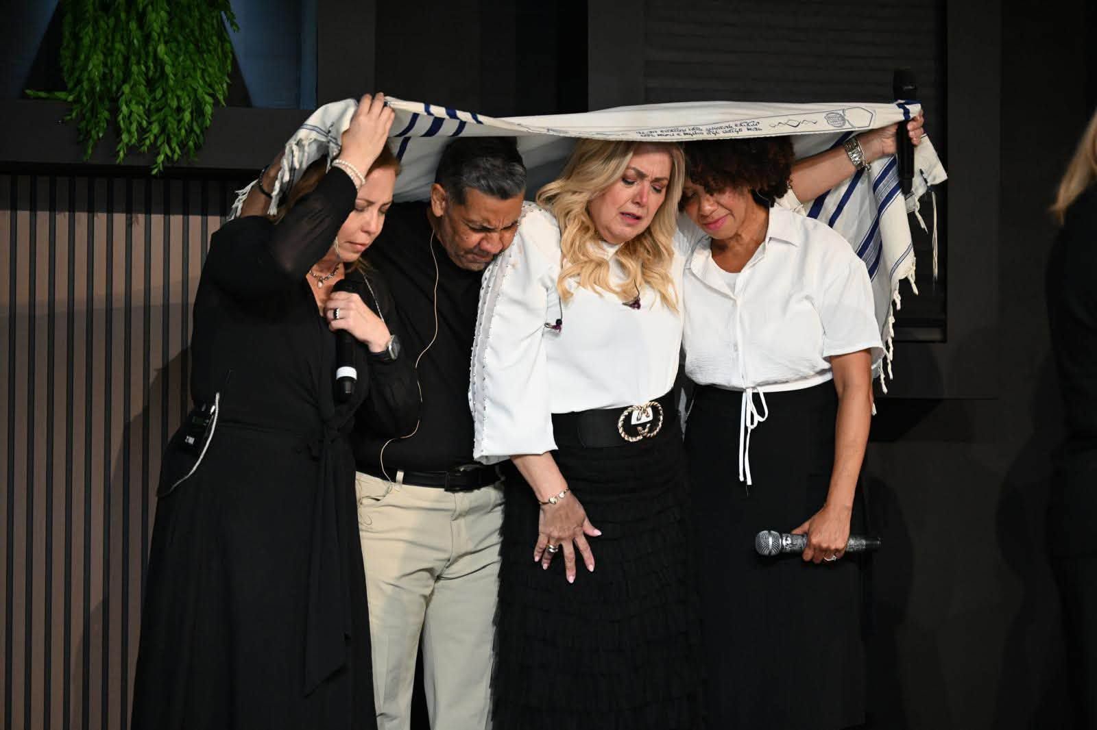 Líderes de la congregación orando juntos bajo un talit en el altar