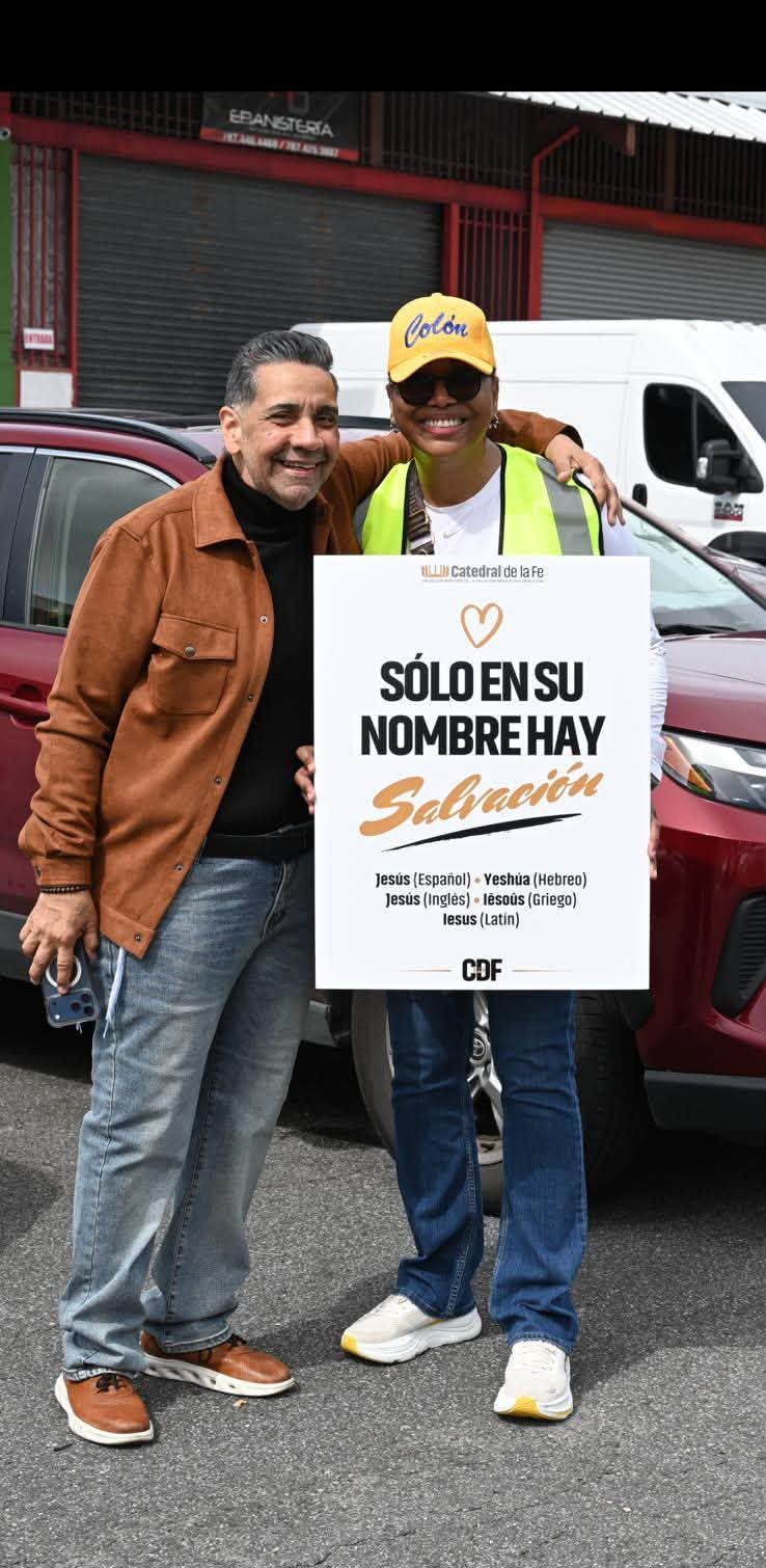 Voluntaria con el Pastor Walter y el letrero Sólo en su nombre hay salvación